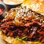 Close-up of a turkey burger on a bun with sesame seeds and sauces on a wooden table.