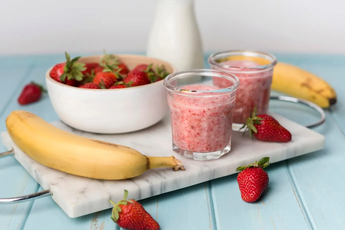 A bowl of strawberries, bananas, and smoothies on a cutting board, perfect for an angel food smoothie recipe.