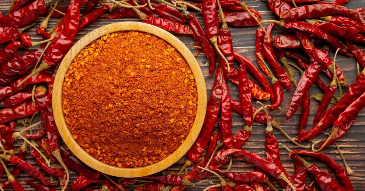A bowl of Chili Powder surrounded by Chili Peppers