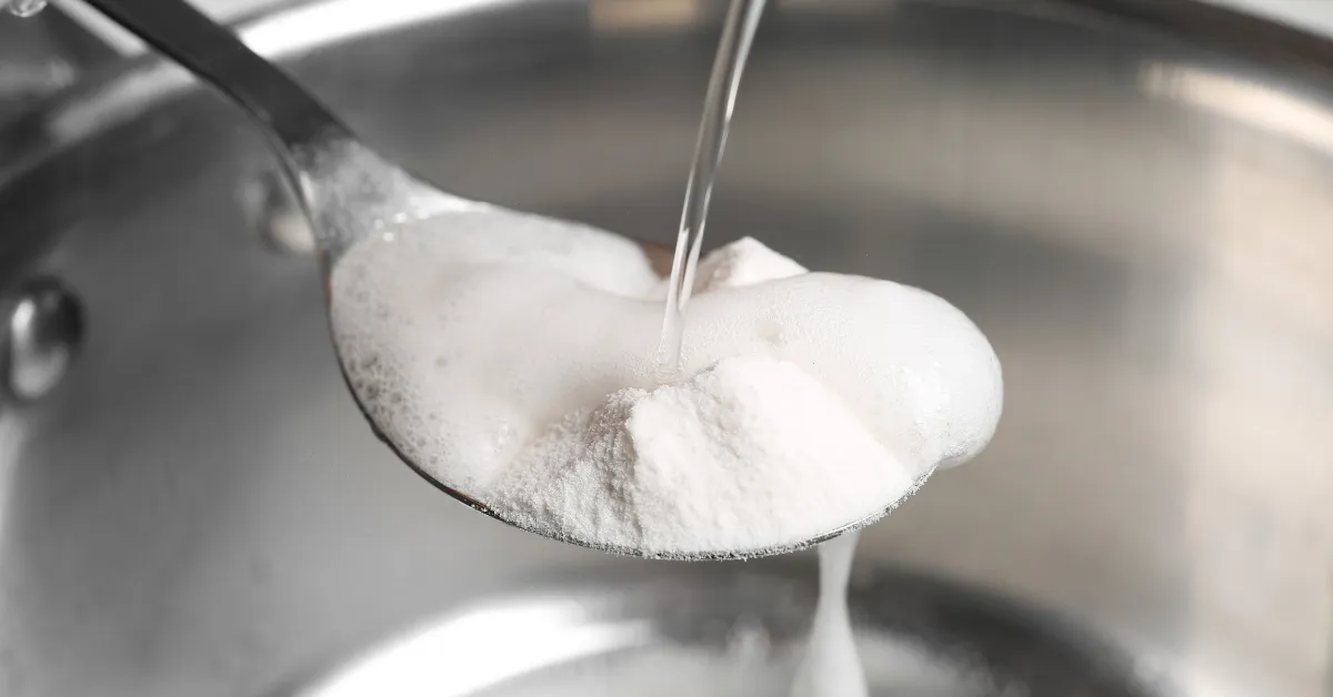 A close-up photo of a spoon with a white powder on it. The powder is baking soda, a leavening agent used in baking.