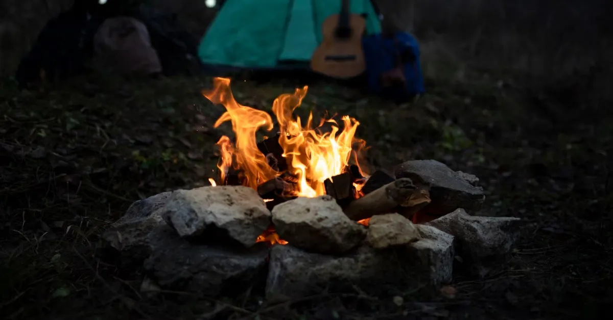 A campfire with a Blackstone griddle and a tent in the background.