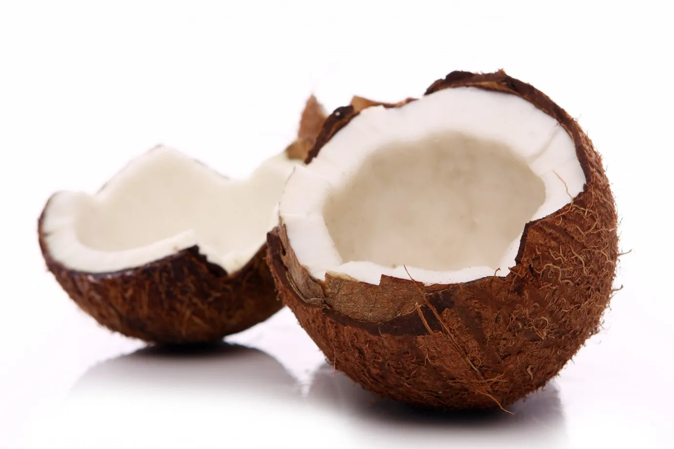 A close-up of a coconut on a white background, showing the coconut's brown husk and white meat.