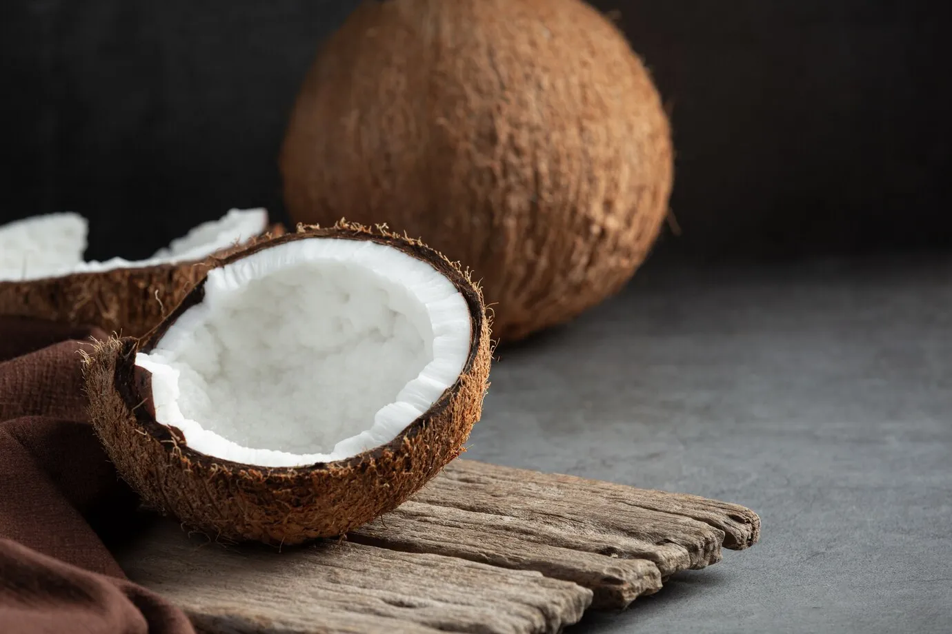 Coconut on wooden cutting board, versatile fruit used in cooking, baking, and skincare.