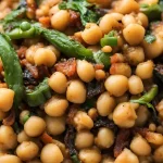 Close-up photo of a bowl of a side dish called garbanzo beans with parsley and tomatoes.