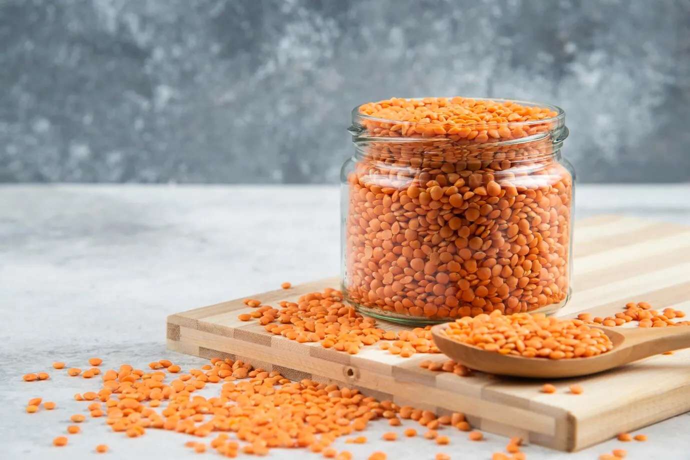 glass jar of red lentils on wooden board for protein without meat
