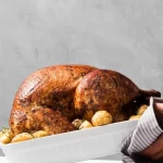 close-up hands putting roasted turkey using Ina Garten way.