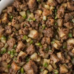 A casserole dish filled with French meat stuffing recipe, a traditional Thanksgiving side dish.