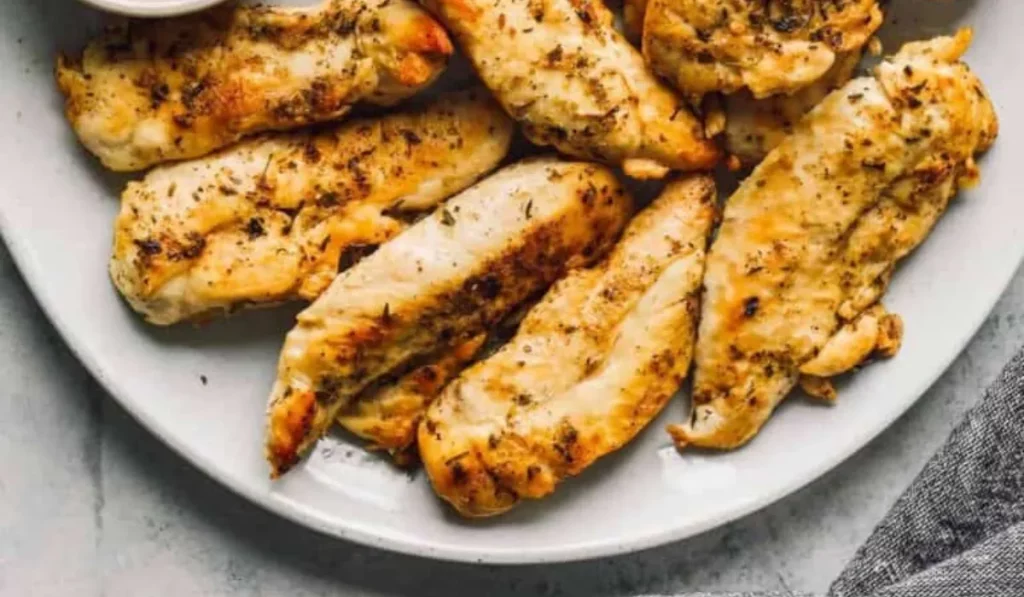 A close-up of juicy chicken tenders made in the Instant Pot, with a side of steamed vegetables.