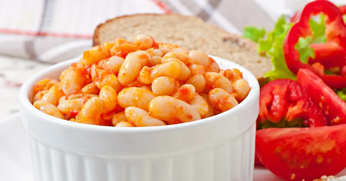 A white bowl filled with baked beans, a good source of protein, fiber, and vitamins.