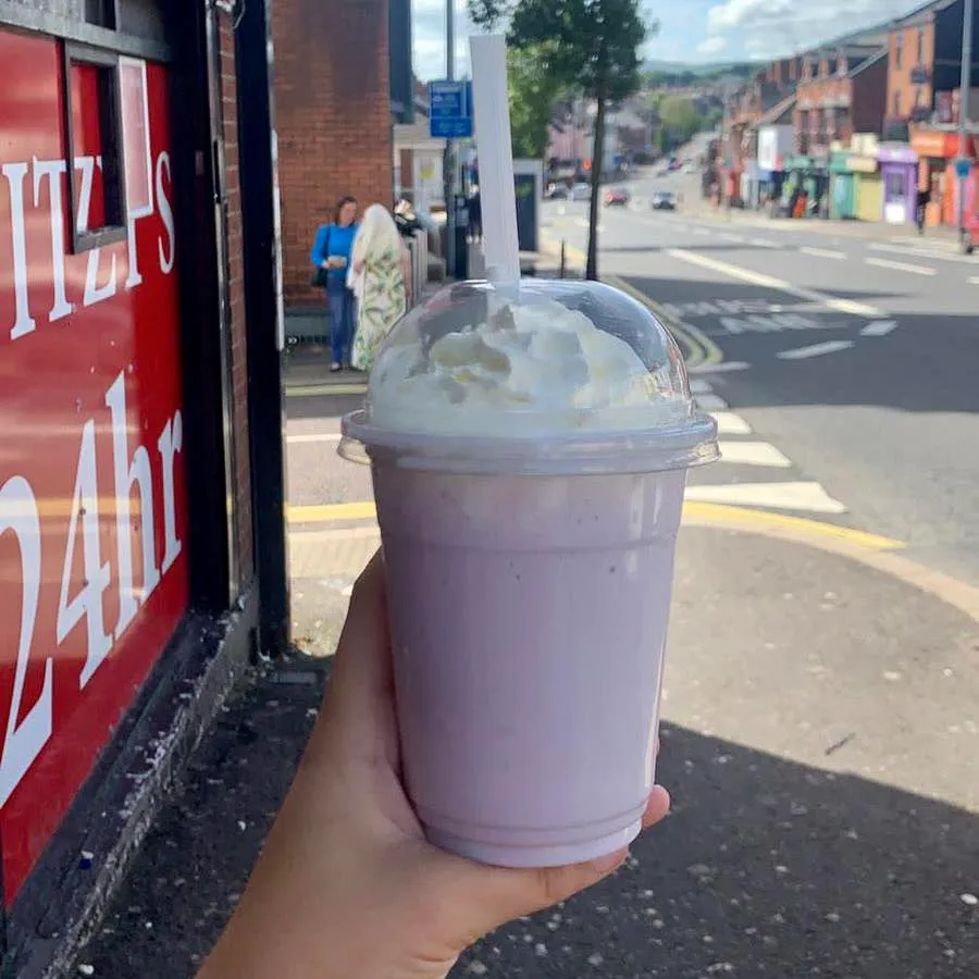 A person holding a grimace shake on the street