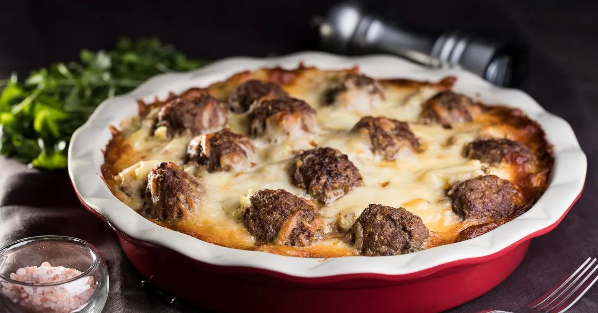 casserole dish filled with pasta, meatballs, and cheese, along with other vegetables such as tomatoes and onions. This is a variation of the classic dump and bake meatball casserole